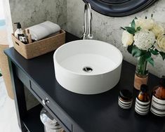 a white sink sitting on top of a black counter next to bottles and soaps