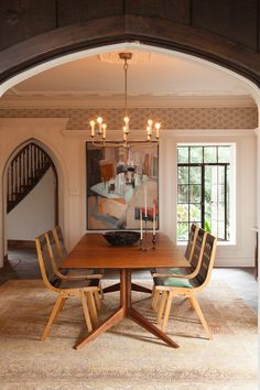 a dining room table with four chairs and a chandelier hanging from the ceiling