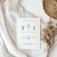 the wedding stationery is laid out next to some dried flowers and a straw hat