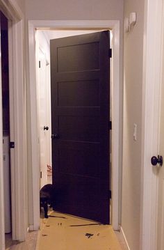 an empty hallway with a black door in the middle and yellow flooring on the other side