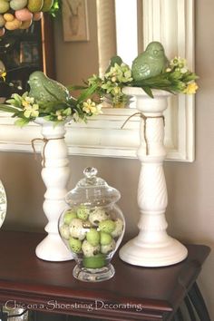 there is a vase with flowers and fruit in it on the table next to a mirror