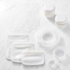 white dishes and containers are arranged on a marble surface