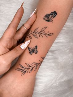 a woman's arm with butterflies and leaves on it