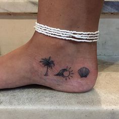 a woman's foot with a small tattoo on the ankle and palm trees in the background