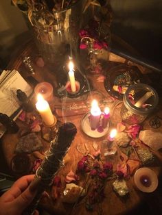 a table topped with candles and other items next to a vase filled with flowers on top of a wooden table