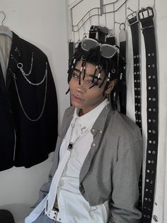 a woman sitting in front of a rack with sunglasses on her head and other accessories hanging from the wall