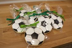 decorated cookies in the shape of soccer balls with green ribbons and bows on a wooden table