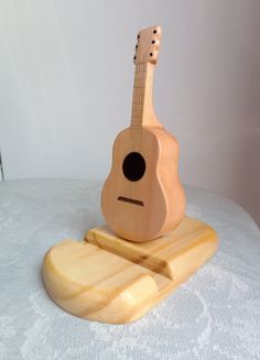 a wooden toy guitar sitting on top of a white tablecloth covered table next to a bottle opener