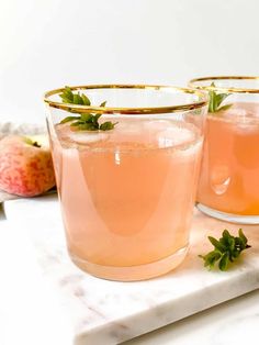 two glasses filled with pink lemonade and garnish on top of a marble counter