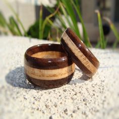 two wooden rings sitting next to each other on top of a sandy surface with grass in the background