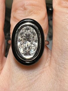 a close up of a person's hand holding a ring with a diamond in it