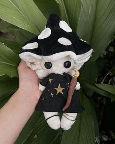 a hand holding a black and white stuffed animal with stars on it's shirt