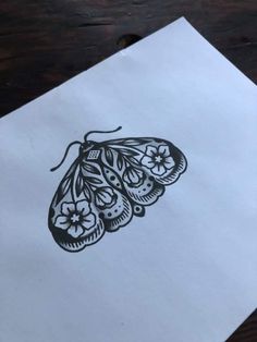 a piece of paper with a drawing of a butterfly on it sitting on a table