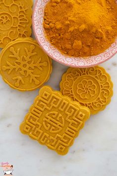 some cookies and orange powder on a white counter top next to a plate with two cookie cutters