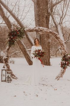 a woman standing in the snow with a wreath around her and flowers on her wedding day