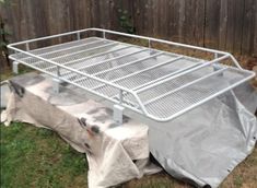 a metal bed frame sitting on top of a grass covered field next to a fence