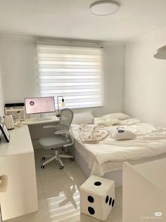 a white room with a bed, desk and computer