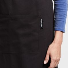 a close up of a person wearing an apron and holding their hands in the pocket