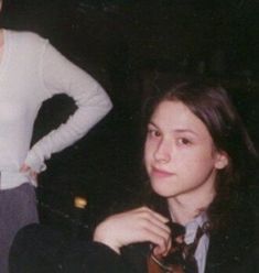 two women standing next to each other with their hands on their hipss and one wearing a white shirt