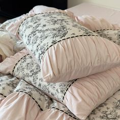 the pillows are piled on top of each other in this bedding set with pink and black designs