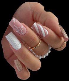 a woman's hand with white and gold nail polishes on her nails, decorated with snowflakes