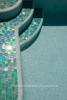 a bench made out of mosaic tiles next to a swimming pool