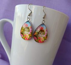 Cute, Adorable Kitten Among Flowers Handmade Cat Themed Glass Earrings A purrfect gift for any animal lover or cat lover. Chic Bold and Unique. Measures 0.98 inches in length and 0.70 inches in width. Comes with First Class Free shipping.. Colors may vary due to monitor and lighting differences. Nickel-free Cat Ears Earrings As Gift, Nickel-free Cat Ears Jewelry For Gifts, Nickel-free Cat Ears Jewelry Gift, Hypoallergenic Cat Ears Earrings For Gift, Hypoallergenic Cat Ears Jewelry For Gift, Cute Cat Design Adjustable Earrings, Cute Cat Design Drop Earrings, Adjustable Cute Cat Design Earrings, Cute Adjustable Cat Design Earrings