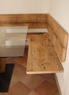 a wooden bench sitting next to a glass table on top of a tiled floor in a room