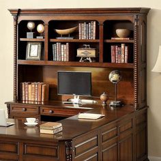 an office desk with bookshelves and a computer on it in front of a wall