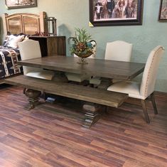 a dining room table and chairs in front of a couch with pictures on the wall