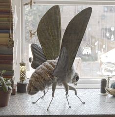 two bugs are standing on their legs in front of a window sill with plants