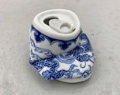 a small blue and white vase sitting on top of a table next to a roll of toilet paper