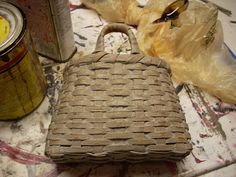 a wicker purse sitting on top of a table next to a can of soda