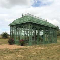 a green metal gazebo sitting on top of a lush green field