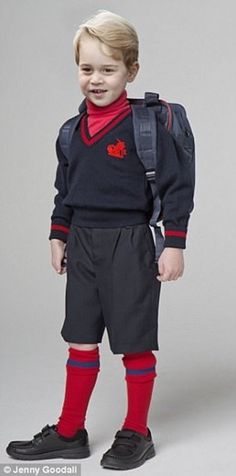 a young boy in school uniform posing for the camera with his back pack over his shoulder