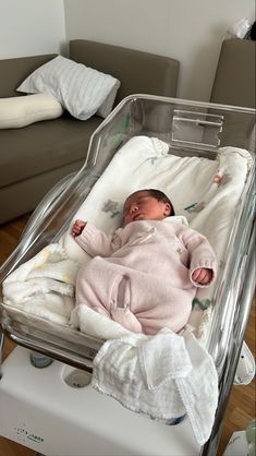 a baby laying in a crib on top of a hard wood floor