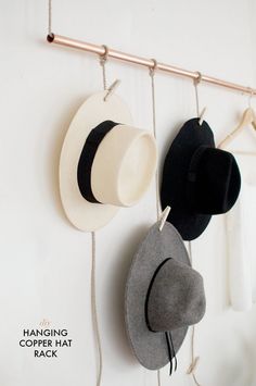 three hats hanging from hooks on a wall