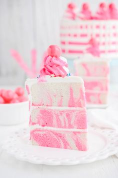 a slice of cake with pink frosting on a white plate next to other cakes