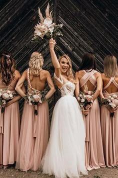 a group of women standing next to each other wearing dresses and holding bouquets in their hands