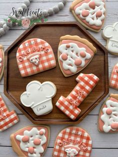 decorated cookies are arranged on a wooden platter, including teddy bears and other items