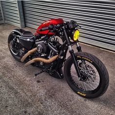 a red and black motorcycle parked in front of a garage