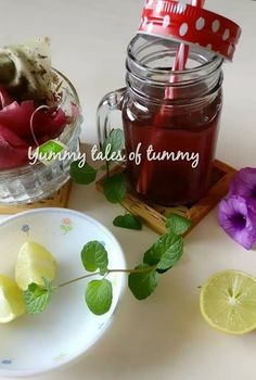 there is a bowl of fruit and a jar of tea on the table with flowers