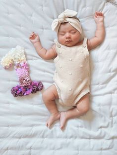 a baby laying on top of a bed next to flowers