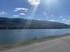 the sun shines brightly over a large body of water with mountains in the background