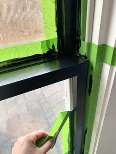 a person is painting the outside of a window with green and white stripes on it