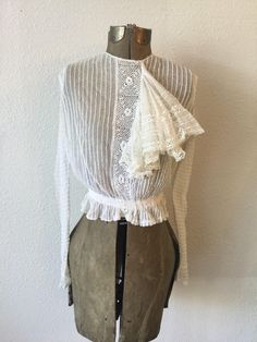 "Vintage Victorian white cotton net and lace blouse with long sleeves and a very large flouncy ruffle coming off a crochet placard down the front. The net has pintuck creating a ribbon effect The sleeves each have two functioning buttons and a small trim of lace. The waist is gathered to create a ruffle around and is backed with ribbon. The whole blouse is lined with net. The blouse buttons down the back with a covered placard to hide the buttons. Single hook and eye at waist. Simple crew neck. Crochet Long Sleeve Top, Crochet Long Sleeve Tops, Blouse With Long Sleeves, Victorian Blouse, Shirtwaist Dress, Brocade Fabric, Vintage Victorian, Blouse Vintage, Lace Blouse