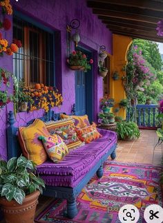 a purple couch sitting on top of a wooden floor next to flowers and potted plants