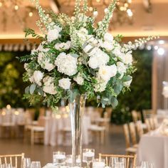 a tall vase filled with white flowers on top of a table