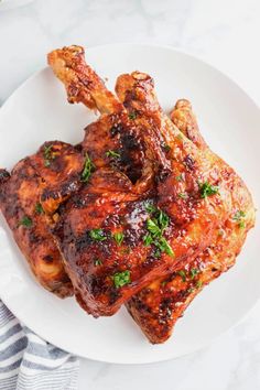 two pieces of chicken on a white plate with parsley and garlic garnish