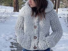 a woman standing in the snow with her hands on her hips, wearing a fuzzy coat